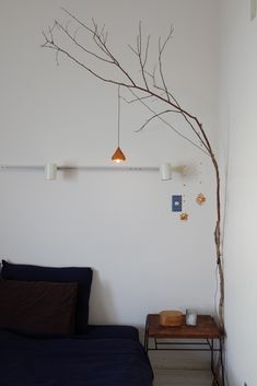 a bedroom with a tree branch hanging from the ceiling and two lights on the wall