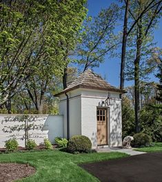 a small white building sitting next to a lush green park