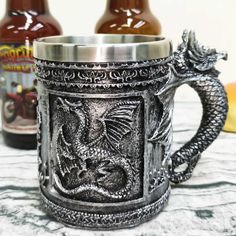 a dragon mug sitting on top of a table next to two bottles