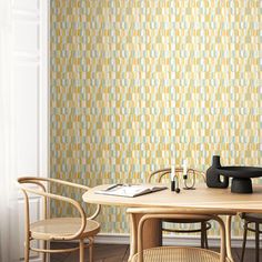 a table and chairs in front of a wallpapered room with a vase on it