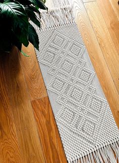 a white rug on the floor next to a potted plant and a wooden floor