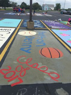 an outdoor basketball court painted with chalk and crayons for the school's logo