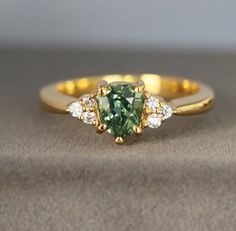 This Ring Design has been hand crafted from 14K Yellow Gold and features a stunning Kite Cut Green Sapphire as the center stone set with Moissanite as side stones. You can upgrade or downgrade the Metal Type to Sterling Silver, 14K, 18K, 22K or Platinum in Yellow, Rose and White Gold. This ring is offered in other various size and we do offer free Resizing Options. The Ring includes a lab report Certified by GIA Alumni Member. You can choose the side stones between Diamonds or Moissanite. Ring D Engagement Rings Kite, Emerald Engagement Ring Green, Parti Sapphire, Lab Report, Bespoke Rings, Three Stone Ring, Etsy Wedding Rings, Sapphire Color, Green Sapphire