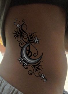 a woman's stomach with a crescent and stars tattoo on the side of her belly