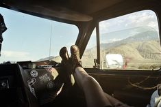 two people are sitting in the driver's seat of a car with mountains in the background