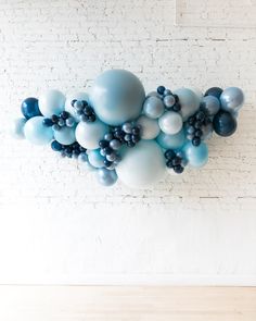 blue and silver balloons are arranged in the shape of heart shapes on a white brick wall