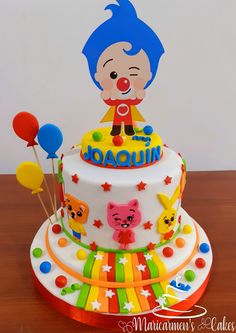 a colorful birthday cake with an image of a clown on the top and balloons around it