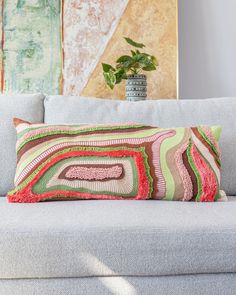 a couch with a pillow on top of it next to a potted green plant