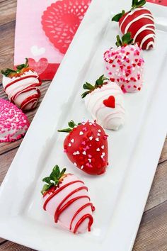 four strawberries are arranged on a white plate