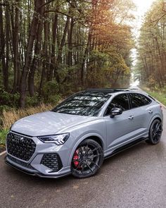 a silver audi suv parked on the side of a road in front of some trees