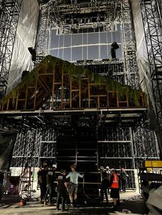 some people are standing around in front of a large structure with scaffolding on it