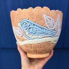 a hand holding a ceramic bowl with blue and white designs on it