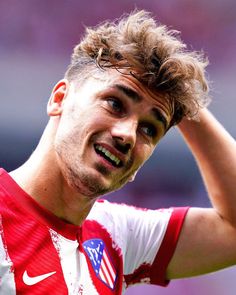 a close up of a soccer player holding his head in one hand and looking off to the side