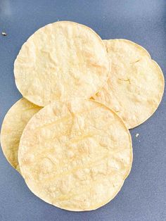 three tortilla chips sitting on top of a blue countertop next to an apple