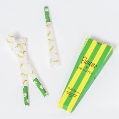 two green and yellow toothbrushes sitting next to each other on a white surface