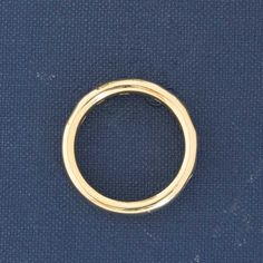 a gold colored ring on a blue surface with no other object in the photo to be seen