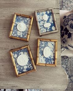 four blue and white coasters sitting on top of a wooden table next to pillows