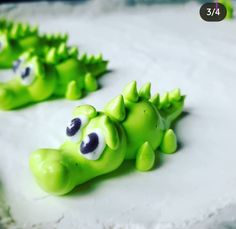 two green alligator figurines sitting on top of a white frosted cake covered in icing