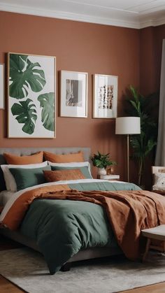 a bed with orange and green sheets in a bedroom next to a chair, lamp and pictures on the wall