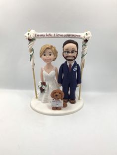 a wedding cake topper with a bride and groom holding a dog on the swing