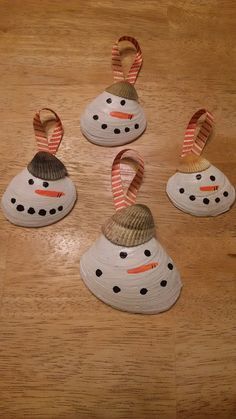 four snowmen with hats and scarfs on top of a wooden table next to each other