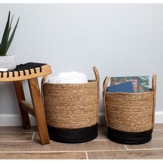 two woven baskets sitting on top of a wooden floor next to a table with books