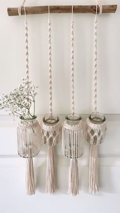 three vases with flowers in them are hanging from a wooden beam on the wall