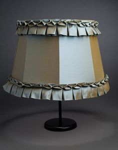 a lamp that is on top of a black base with a white and tan shade