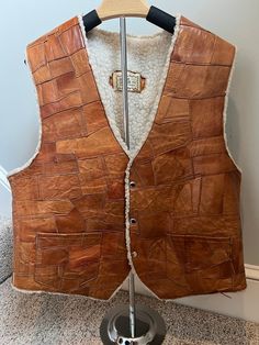 A rare GEM! Vintage 1970s patchwork leather vest with shearling lining. Made in Mexico, size 46. Has side pockets.  MEASUREMENTS (garment measured flat): Shoulder to shoulder: 16" Shoulder to bottom (front): 25" Back (neck to bottom of vest): 33" Arm Hole: 11" Please read description carefully and view all photos. I describe and photograph all condition issues that I am aware of. I do my best to research and give the most accurate information regarding the item, but no one is perfect! Please do your own research if you are unsure about the item(s). Additional photographs are available upon request. If you have questions about any item, please contact me before purchasing. Unless stated otherwise, all vintage clothing items are pre-owned, one in stock, and are sold as-is with no warranty. I Brown Rugged Vest For Winter, Brown Rugged Winter Vest, Rugged Brown Winter Vest, Brown Sleeveless Vest With Faux Fur Lining, Leather Winter Vest With Pockets, Vintage Leather Vest Outerwear, Brown Patchwork Vest For Fall, Leather Gilet, 70s Patchwork