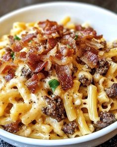 a white bowl filled with macaroni and cheese covered in meat, bacon and parmesan