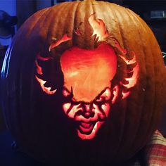 a carved pumpkin with an image of a demon on it's face and hands