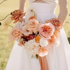 a bride holding a bouquet of peach and white flowers