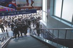 many people are walking up and down the stairs in front of a large screen tv