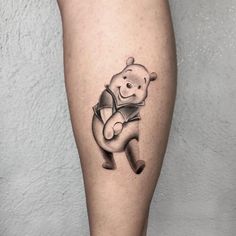 a black and white tattoo of a teddy bear holding a book on the leg,