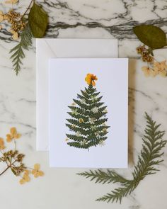 a card with a pine tree on it and yellow flowers in the corner next to it