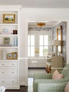 a living room filled with furniture next to a white book shelf and door leading to another room