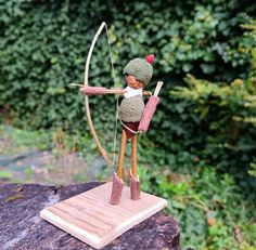 a wooden sculpture of a person with a bow and arrow on top of a rock