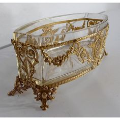 an ornately decorated glass and gold tray on white table top with the lid open