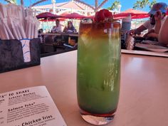 a tall glass filled with liquid sitting on top of a table next to a menu