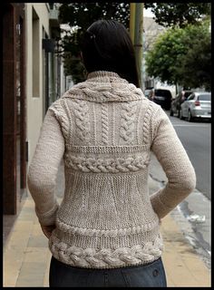 a woman is standing on the sidewalk in front of a building with her back turned to the camera