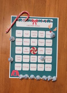 a christmas bingo board with candy canes and candies around it on a wooden table