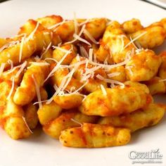 a white plate topped with cheesy pasta covered in sauce and parmesan cheese