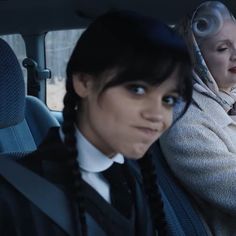 two women sitting in the back seat of a car, one with her head up