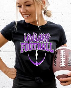 a woman holding a football in her right hand and wearing a black shirt with the words indiana football on it