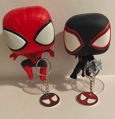 two spider - man keychains sitting next to each other