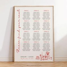 a red and white wedding seating chart on a wooden frame in front of a wall