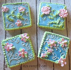 four decorated square cookies sitting on top of a wooden table next to eachother