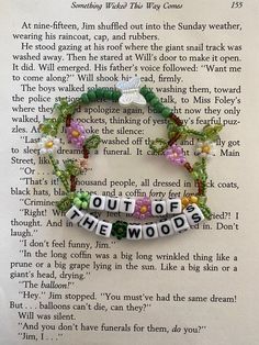 a book page with words written in white letters and flowers on it, along with an ornament that says out of the woods