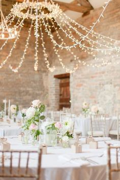 an image of a table set up for a wedding party with lights hanging from the ceiling