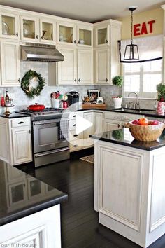 a kitchen filled with lots of white cabinets and black counter top space next to an oven